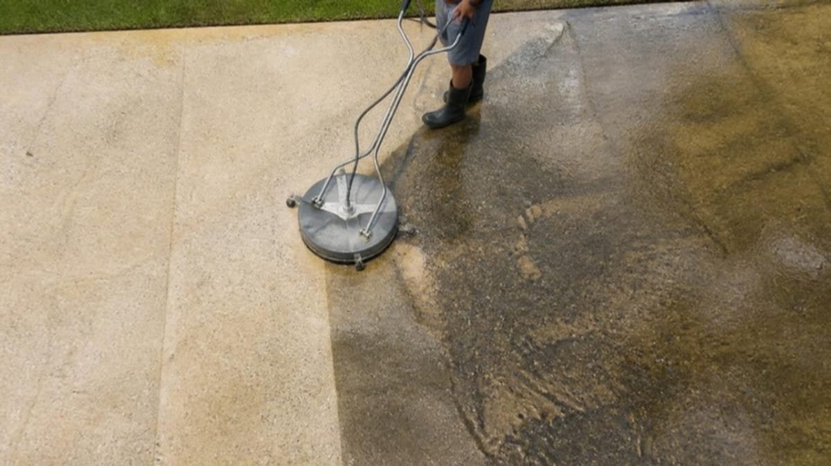 Surface cleaner washing a concrete driveway, half clean and half dirty